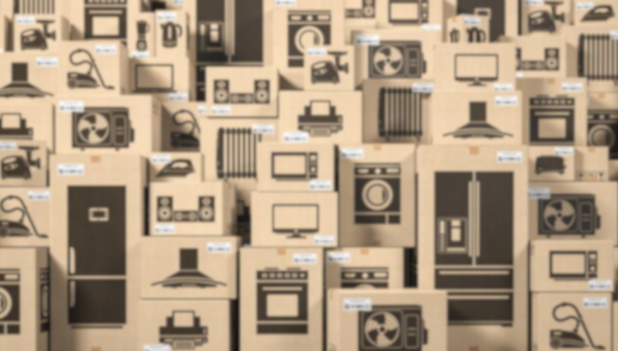 Stosy kartonów z nadrukami sprzętu AGD i RTV, takiego jak telewizory, pralki, lodówki i odkurzacze.