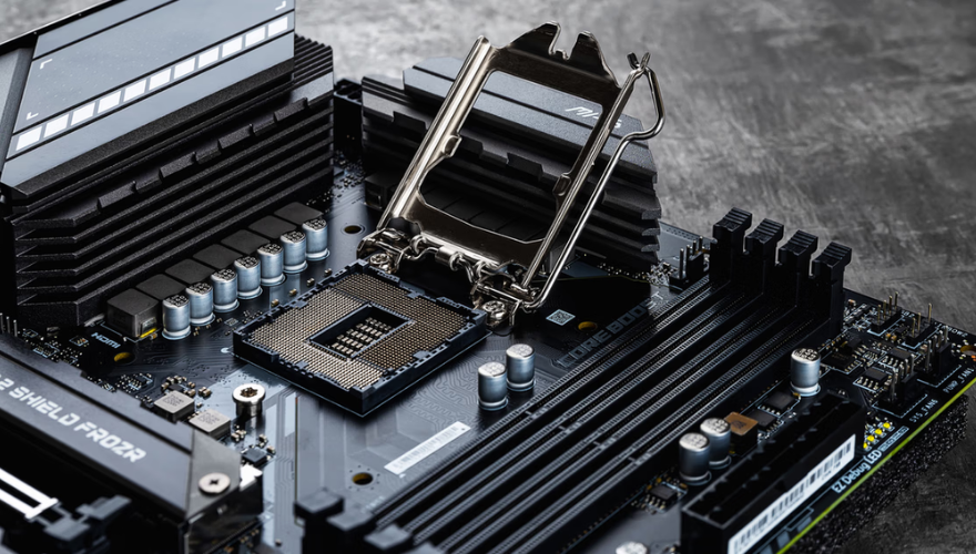 Płyta główna i elementy elektroniczne na stole roboczym.