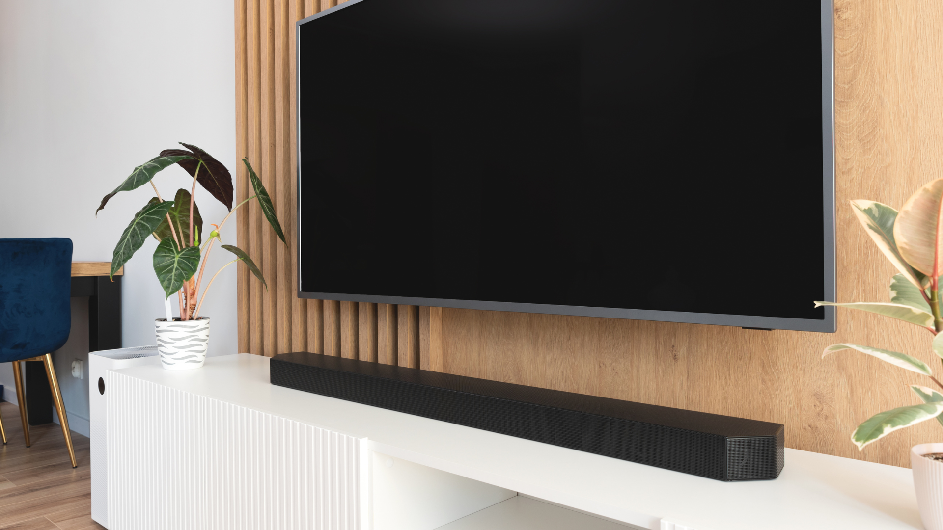 Soundbar pod telewizorem i subwoofer przy ścianie – szeroki kadr z miejscem na overlay